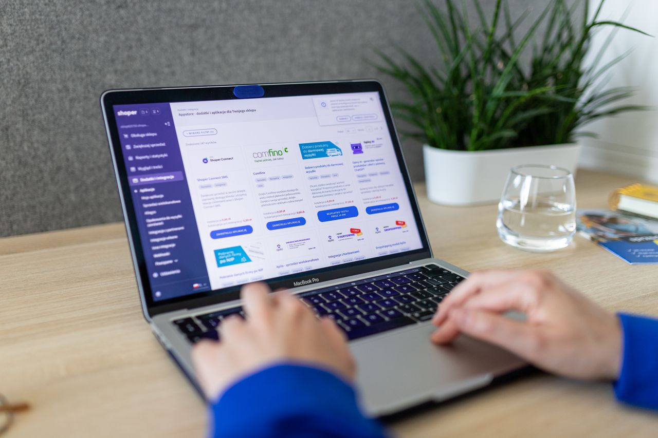 Close-up of hands on a laptop browsing an e-commerce site in a modern office.